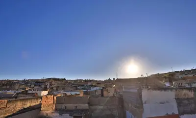 a view of a city with the sun in the sky at house Merinides fes in Fès