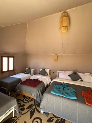 a room with three beds in a tent at One Thousand and One Night Luxury Camp in Merzouga