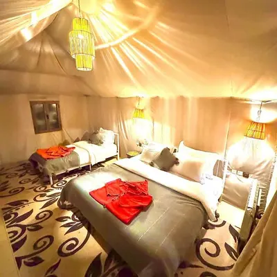 a bedroom with two beds with red clothes on them at One Thousand and One Night Luxury Camp in Merzouga