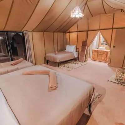 a room with a bed and a chair in a tent at One Thousand and One Night Luxury Camp in Merzouga