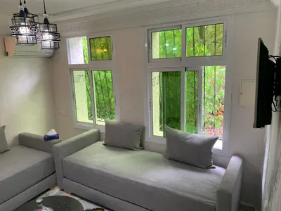 a living room with two couches and three windows at chez saad in Fès