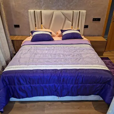 a large bed with purple comforter and blue pillows at Appartement agadir bay bien ensoleillé in Oulad Akkou