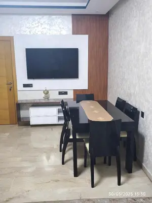 a dining room with a table and chairs and a television at Appartement agadir bay bien ensoleillé in Oulad Akkou