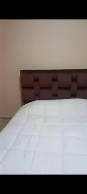a close up of a white bed with a brown headboard at Apartamento en Rabat al lado del Mar in Oulad Akkou