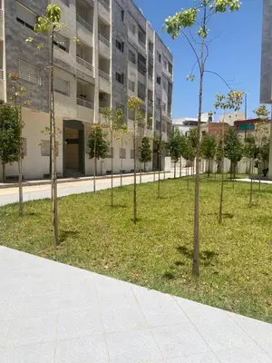 a row of trees in a park in front of a building at Meknès cosy près Médina in Meknès