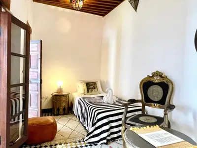 a small bedroom with a bed and a chair at Charming Riad Medina View 4 AC Bedrooms Panoramic Terrace Central Fez in Fès al Bali