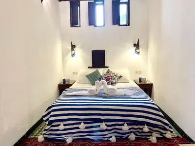 a bedroom with a bed with a blue and white striped blanket at Charming Riad Medina View 4 AC Bedrooms Panoramic Terrace Central Fez in Fès al Bali