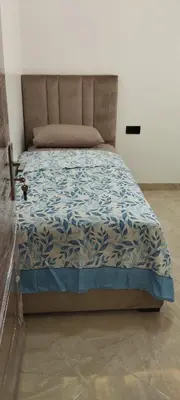 a bedroom with a bed with a blue comforter at شقة مفروشة 3 غرف حمامين مطبخ وصالون in Oulad Akkou