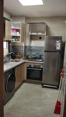 a kitchen with a stainless steel refrigerator and a stove at شقة مفروشة 3 غرف حمامين مطبخ وصالون in Oulad Akkou