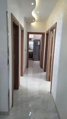 a hallway of a house with doors and a refrigerator at شقة مفروشة 3 غرف حمامين مطبخ وصالون in Oulad Akkou