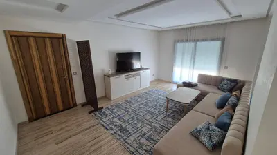 a living room with a couch and a tv at Schöne Ferienwohnung mit Pools in Oulad Akkou