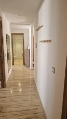 a hallway with white walls and a wooden floor at Schöne Ferienwohnung mit Pools in Oulad Akkou