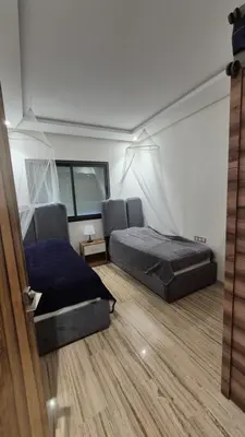 a bedroom with two beds and a wooden floor at Schöne Ferienwohnung mit Pools in Oulad Akkou