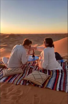 a man and woman sitting at a table in the desert at Fantastic desert camp in Oulad Akkou