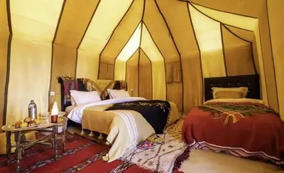 a room with two beds and a table in it at Fantastic desert camp in Oulad Akkou