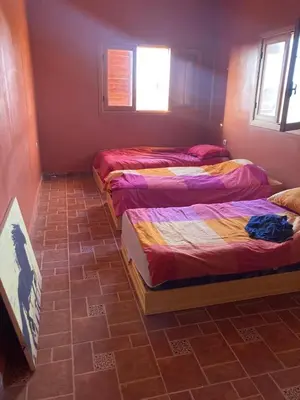 two beds in a room with a brick floor at Villa Syam in Tiflet