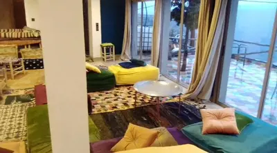 a room with green and yellow pillows and a large window at Refuge AIT M'HAMED