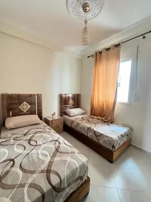 a bedroom with two beds and a chandelier at Diyar tanger in Oulad Akkou
