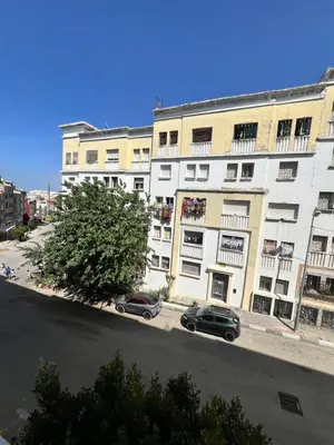 two cars parked in front of a large white building at Diyar tanger in Oulad Akkou
