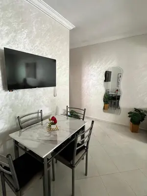 a dining room table with chairs and a tv on a wall at Diyar tanger in Oulad Akkou