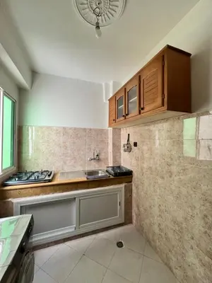 a kitchen with a sink and wooden cabinets at Diyar tanger in Oulad Akkou