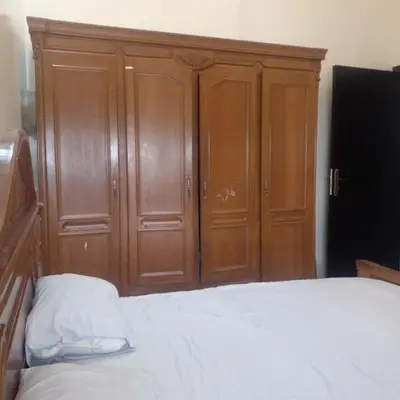 a bedroom with a bed and wooden cabinets at ديار البوغاز in Oulad Akkou