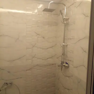 a bathroom with a shower with white tiles at ديار البوغاز in Oulad Akkou