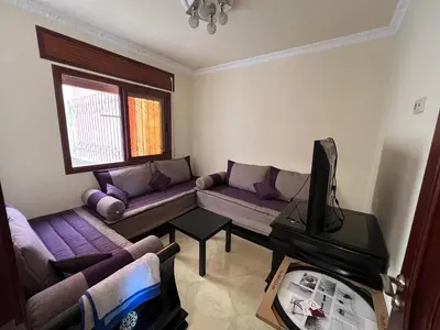 a living room with purple couches and a tv at Oum kaltoum in Oulad Akkou
