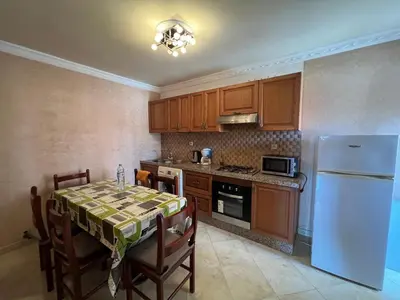 a kitchen with a table and a white refrigerator at Oum kaltoum in Oulad Akkou