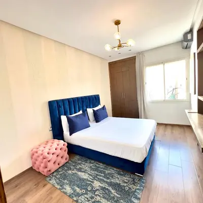a bedroom with a large bed with a blue headboard at Appartement avec vue sur Parc champs de course et Wifi 200 Mo in Oulad Akkou