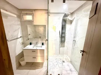 a white bathroom with a shower and a sink at Appartement avec vue sur Parc champs de course et Wifi 200 Mo in Oulad Akkou