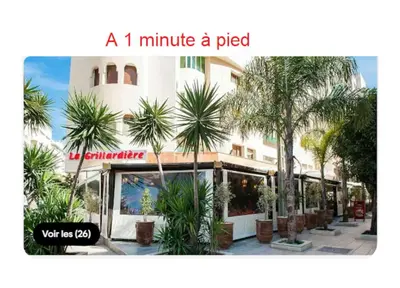 a minute a pep sign on a building with palm trees at Appartement avec vue sur Parc champs de course et Wifi 200 Mo in Oulad Akkou