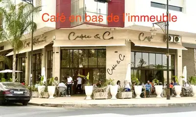 a building with people sitting in chairs outside of it at Appartement avec vue sur Parc champs de course et Wifi 200 Mo in Oulad Akkou