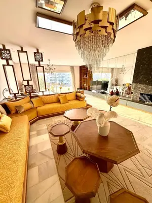 a living room with a yellow couch and a chandelier at Appartement avec vue sur Parc champs de course et Wifi 200 Mo in Oulad Akkou