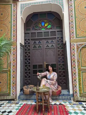 a woman sitting in front of a door at Le panoramique de Fes in Fès