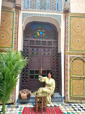 a woman is sitting in front of a building at Le panoramique de Fes in Fès