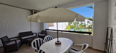 a table and chairs with an umbrella on a balcony at Apartamentos rent me in Oulad Akkou