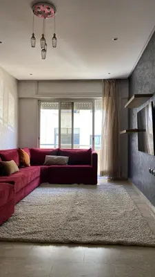 a living room with a red couch and a rug at Marina Retreat in Oulad Akkou