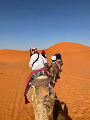 a group of people riding elephants in the desert at Merzouga heritage camp in Merzouga