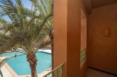 a palm tree next to a swimming pool at Amanar Hôtel & Spa Ouarzazate in Ouarzazate