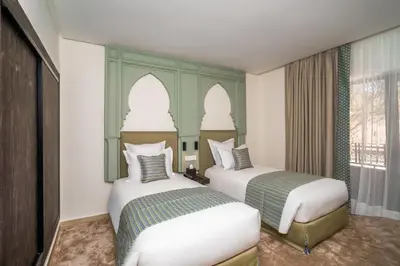 two beds in a hotel room with two beds at Amanar Hôtel & Spa Ouarzazate in Ouarzazate