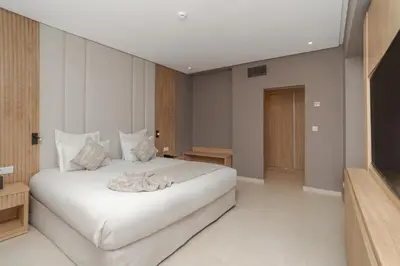 a bedroom with a white bed and a television at Amanar Hôtel & Spa Ouarzazate in Ouarzazate