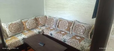 a couch with pillows on it with a table at appartement familial in Oulad Akkou