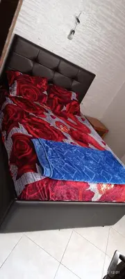 a bed with a red and blue blanket on it at appartement familial in Oulad Akkou