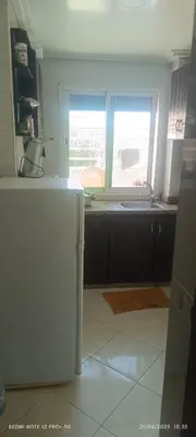 a kitchen with a refrigerator and a window at appartement familial in Oulad Akkou