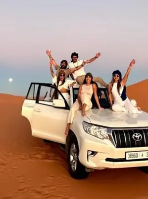 a group of people sitting on the back of a truck in the desert at Merzouga white camp in Merzouga