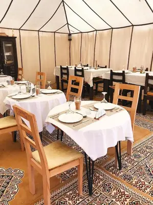 a dining room with tables and chairs in a tent at Merzouga white camp in Merzouga