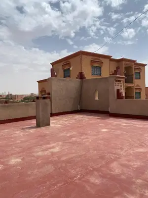 a house on top of a roof with a red concrete lot at Kasbah in El Hart