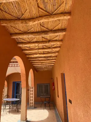 a patio with a wooden ceiling with tables and chairs at Kasbah in El Hart