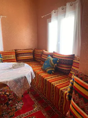 a couch with colorful pillows in a room with a window at Kasbah in El Hart